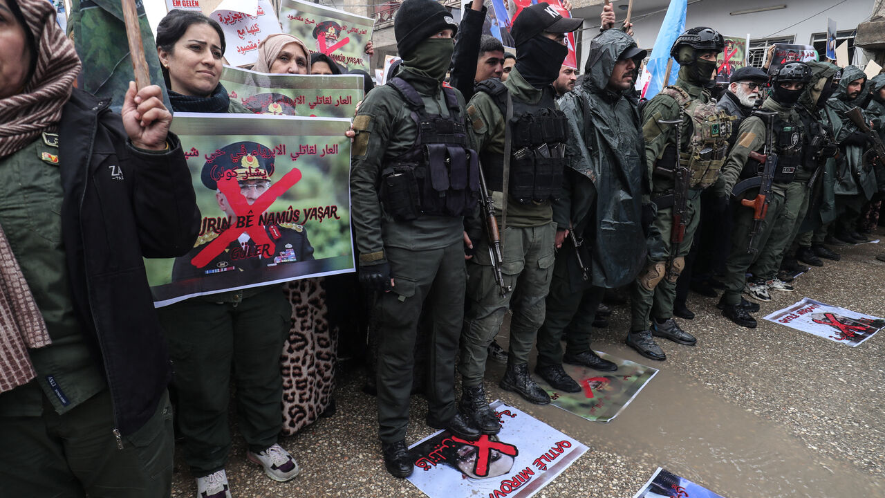 Members of the Kurdish forces hold a portrait of Turkish Defense Minister Yasar Guler which reads "Shame on the killers of innocents in the Sheikh Maqsoud neighborhood" during a protest by Syrian Kurds against violence they say was committed by Syrian government forces during recent clashes in Aleppo's Kurdish neighbourhoods, in the Kurdish-controlled northeastern city of Qamishli on Jan. 13, 2026. 