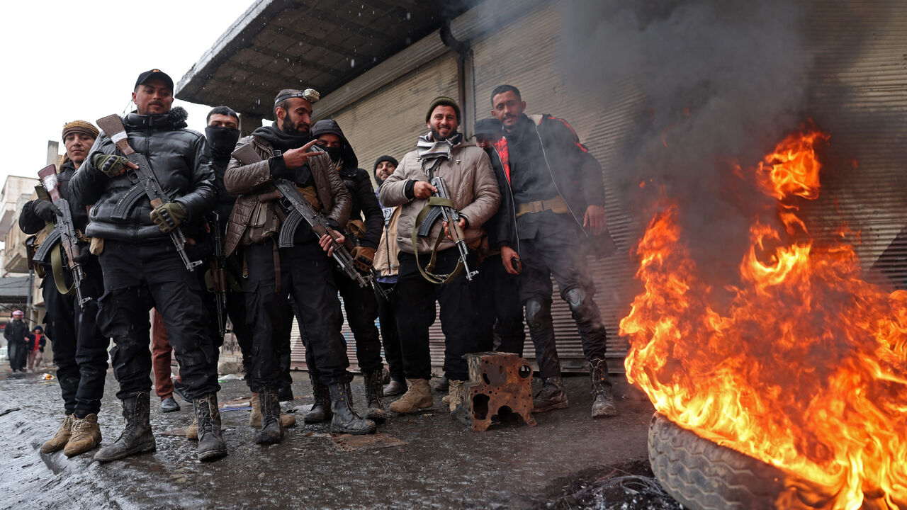 Syrian government troops stand guard next to a burning tyre along a street of Tabqa, in Raqa province, on the southwestern banks of the Euphrates on Jan. 18, 2026. 