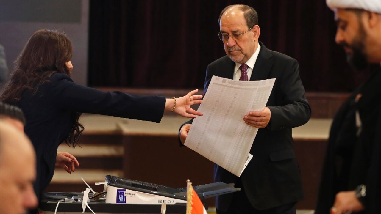 Former Iraqi prime minister Nouri al-Maliki holds the ballot paper at a polling station in Baghdad on November 11, 2025 during parliamentary elections