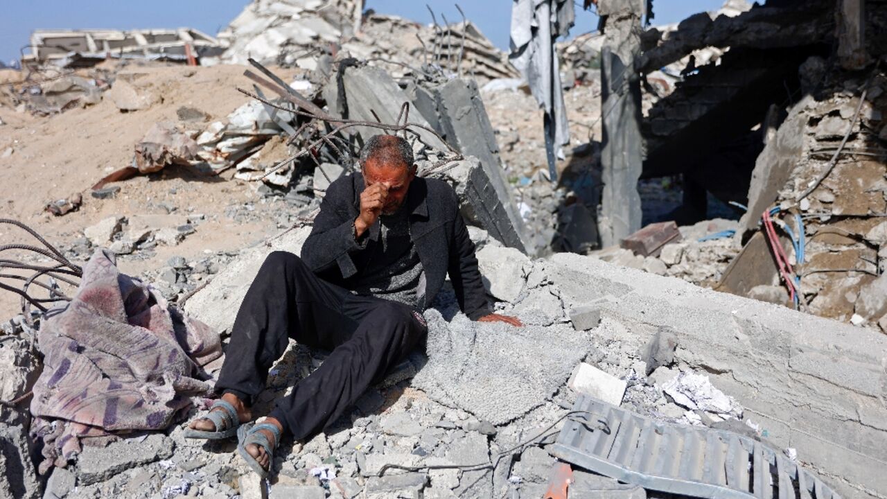 A man sits in the rubble of Sheikh Radwan police station in Gaza City after the Israeli air strike