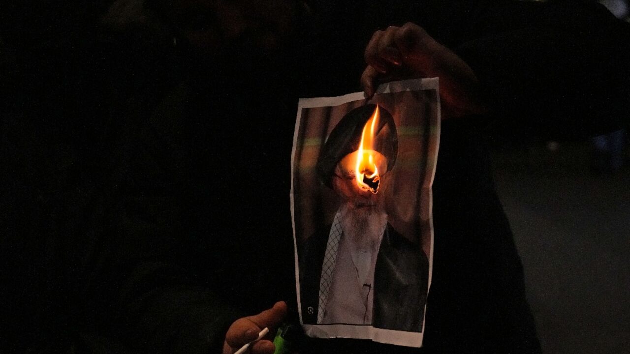 A protestor in London burns an image of Iran's spiritual leader Ayatollah Ali Khamenei at a rally in support of demonstrators in Iran