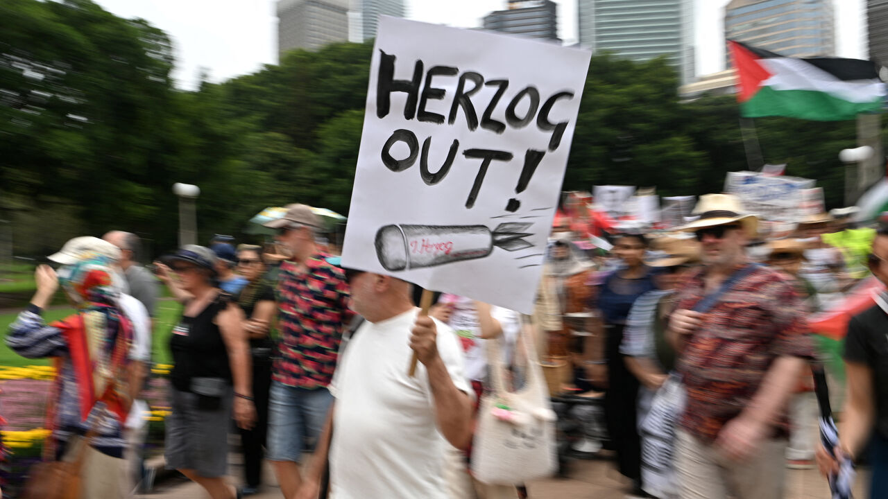 A man holds a placard during a protest against Israeli President Isaac Herzog's upcoming visit to Australia, at Hyde Park, in Sydney, Australia, February 1, 2026. REUTERS/Flavio Brancaleone
