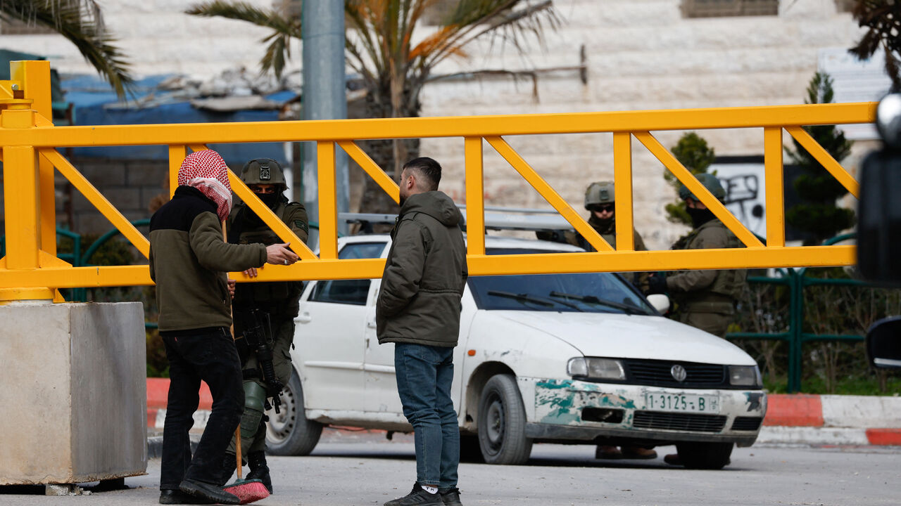 A Palestinian man speaks to an Israeli soldier during an Israeli military multi-day raid in Hebron, in the Israeli-occupied West Bank January 21, 2026. REUTERS/Mussa Qawasma