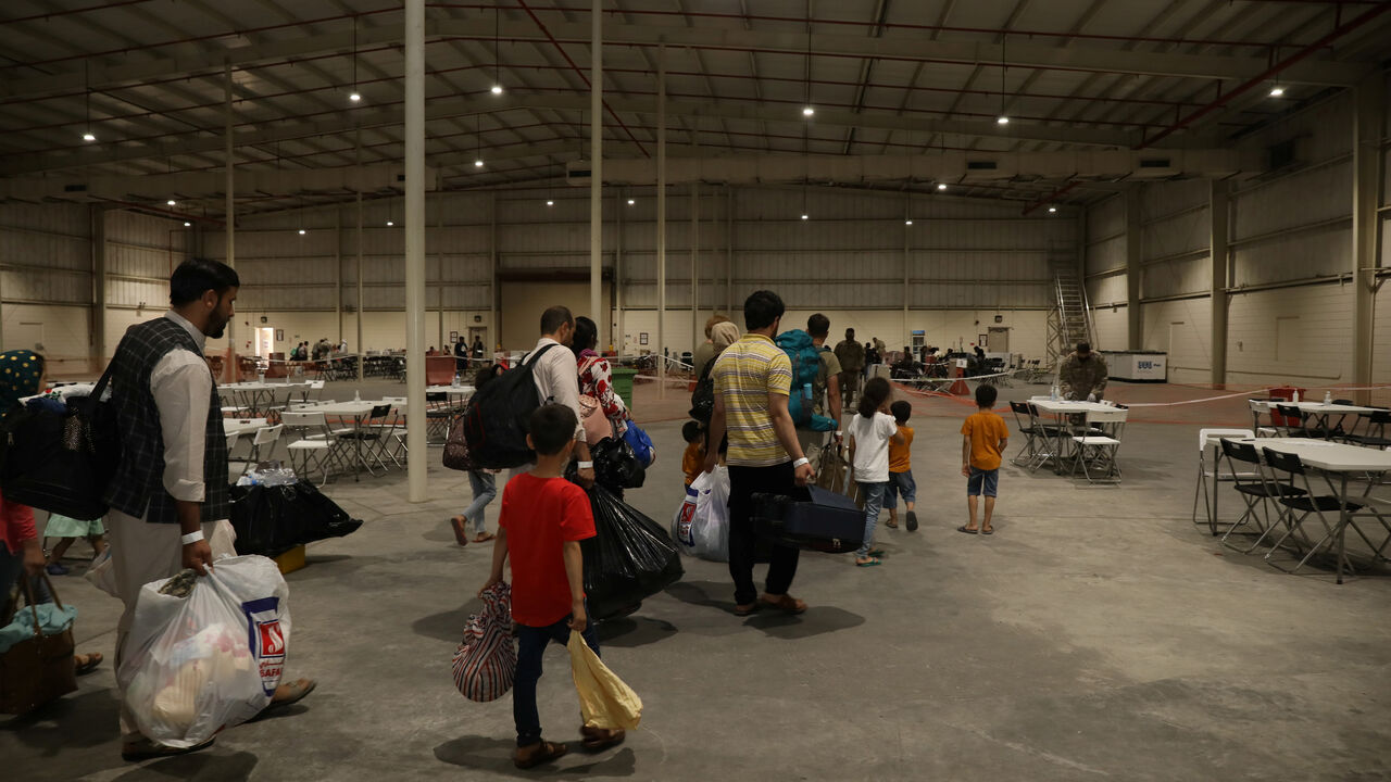 Special Immigrants from Afghanistan walk through the in-processing building after their evacuation at Camp As Sayliyah, Qatar, August 20, 2021. Picture taken August 20, 2021.  U.S. Army/Sgt. Jimmie Baker/Handout via REUTERS