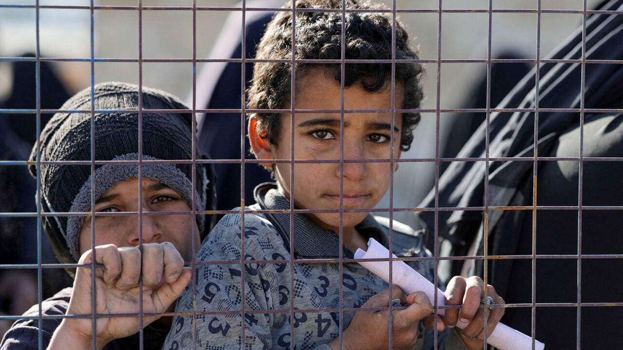 Children, part of a group of detainees, look through a fence at al-Hol camp after the Syrian government took control of it following the withdrawal of Syrian Democratic Forces (SDF), in Hasaka, Syria, January 21, 2026. REUTERS/Khalil Ashawi