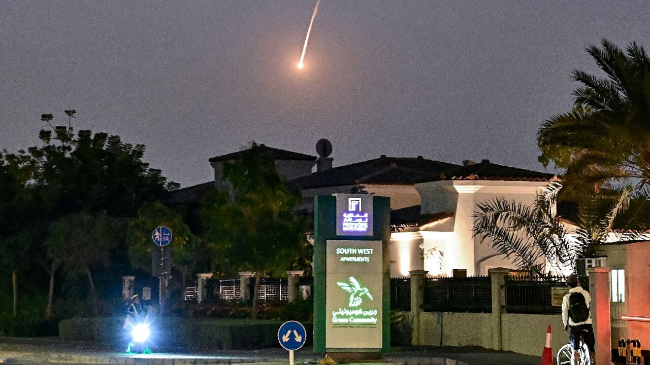 A cyclist watched as a projectile falls over Dubai during an Iranian missile strikes triggered by a wave of US and Israeli strikes on Iran  