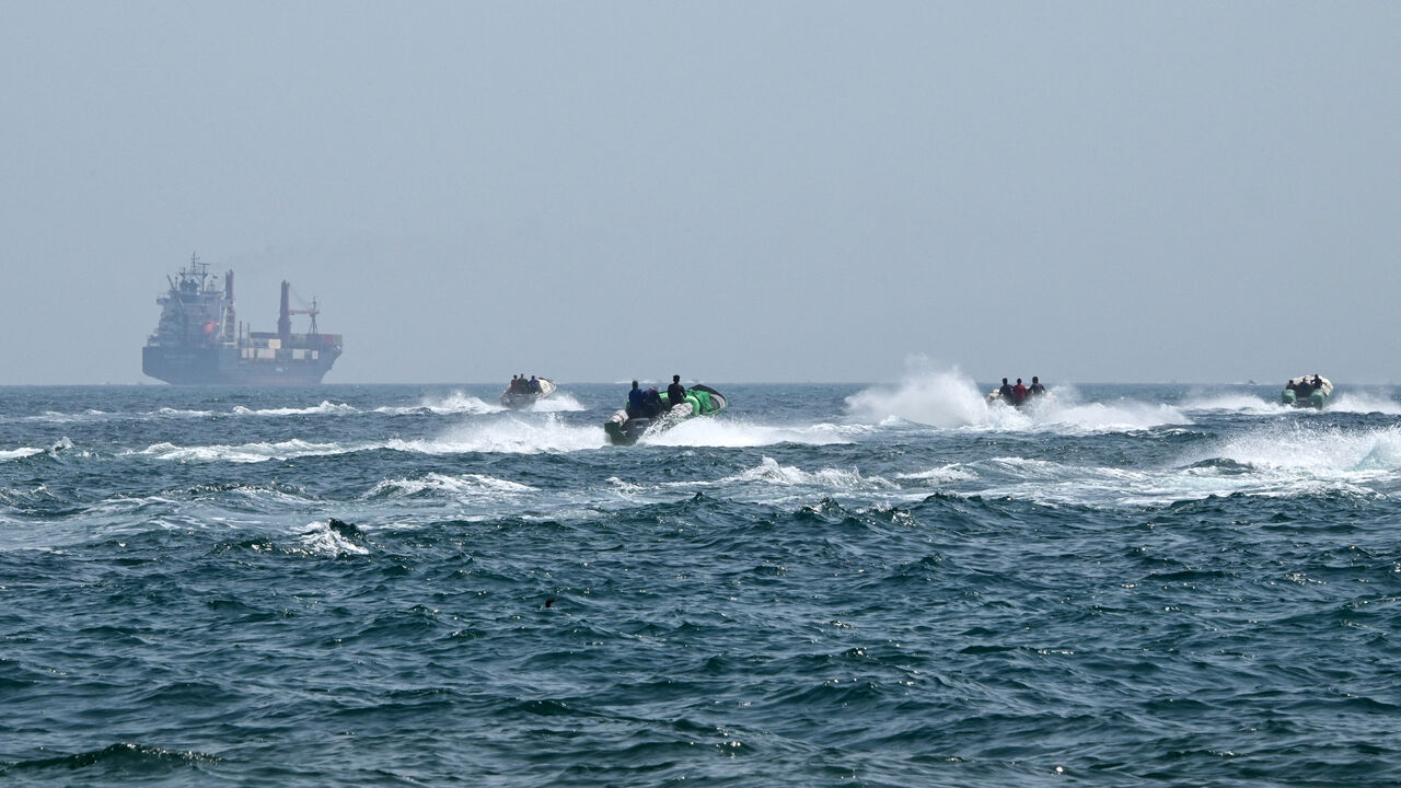 Small boats loaded with merchandise sail past the St Kitt's and Nevis-flagged container ship Marsa Victory in the waters of the Strait of Hormuz off the coast of Khasab in the northern Musandam Peninsula, Oman, June 25, 2025.