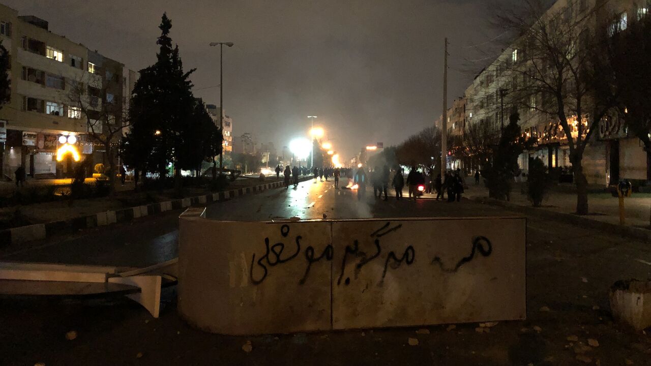 Iranian protesters block a street as a slogan against Iran's supreme leader is spray-painted nearby during a demonstration in Shiraz, Iran, on Jan. 10, 2026. 
