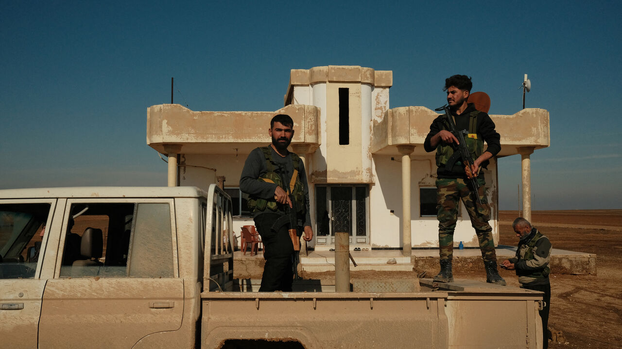 Syrian Democratic Forces fighters stand on a pick-up truck to provide security during an inspection of SDF positions on the Tell Brak frontline in Syria on Jan. 26, 2026.