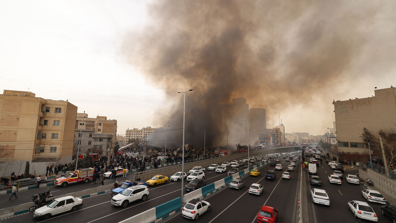 Motorists drive past as firefighters battle a fire that broke out in Jannat Bazaar, west of Tehran on Feb. 3, 2026. 