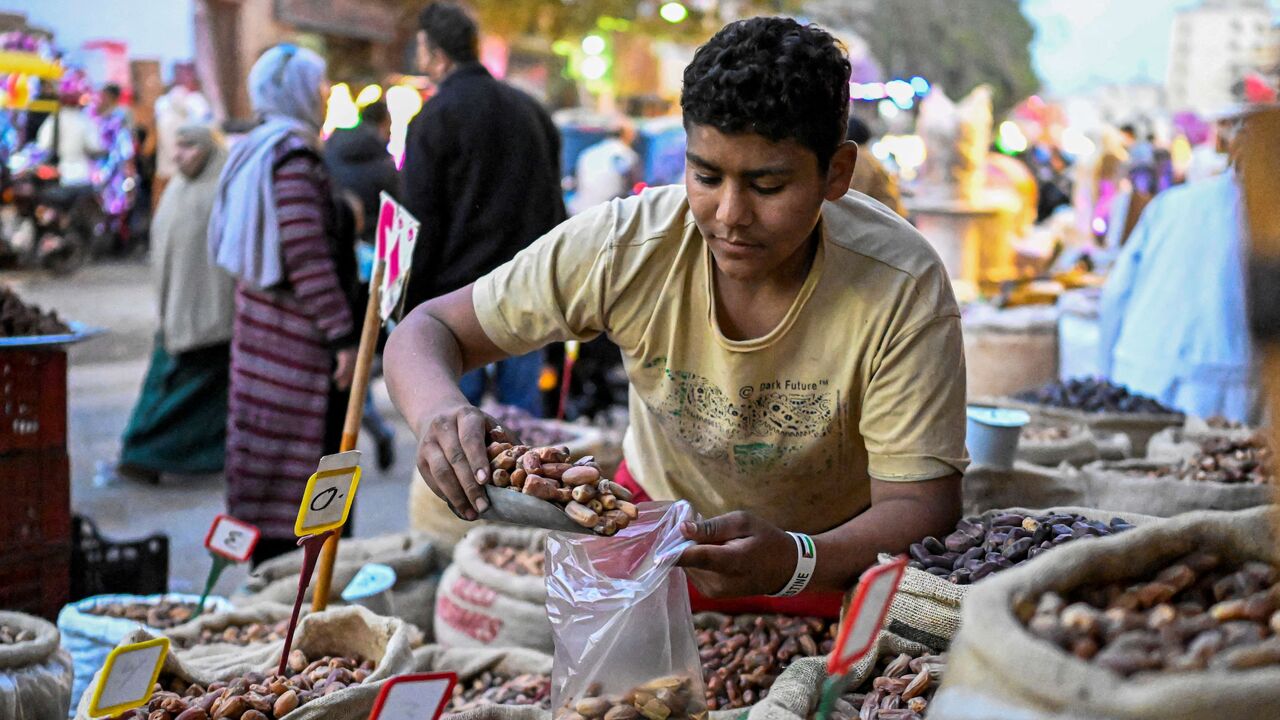 An Egyptian vendor fills dates for a customer at a market in Cairo's central Sayyida Zeinab district on Feb. 12, 2026, as Muslims prepare for the holy fasting month of Ramadan, which begins early next week. 
