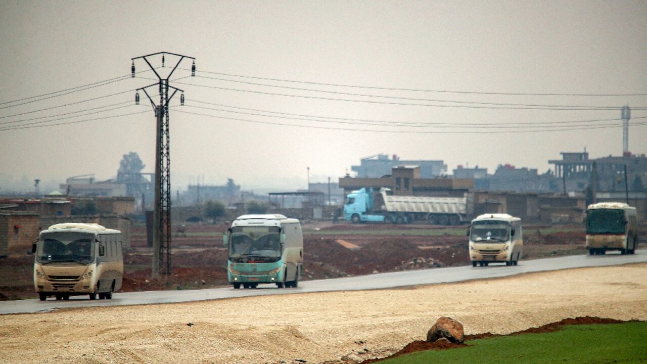 Buses in a US military convoy transporting Islamic State group detainees being transferred to Iraq from Syria