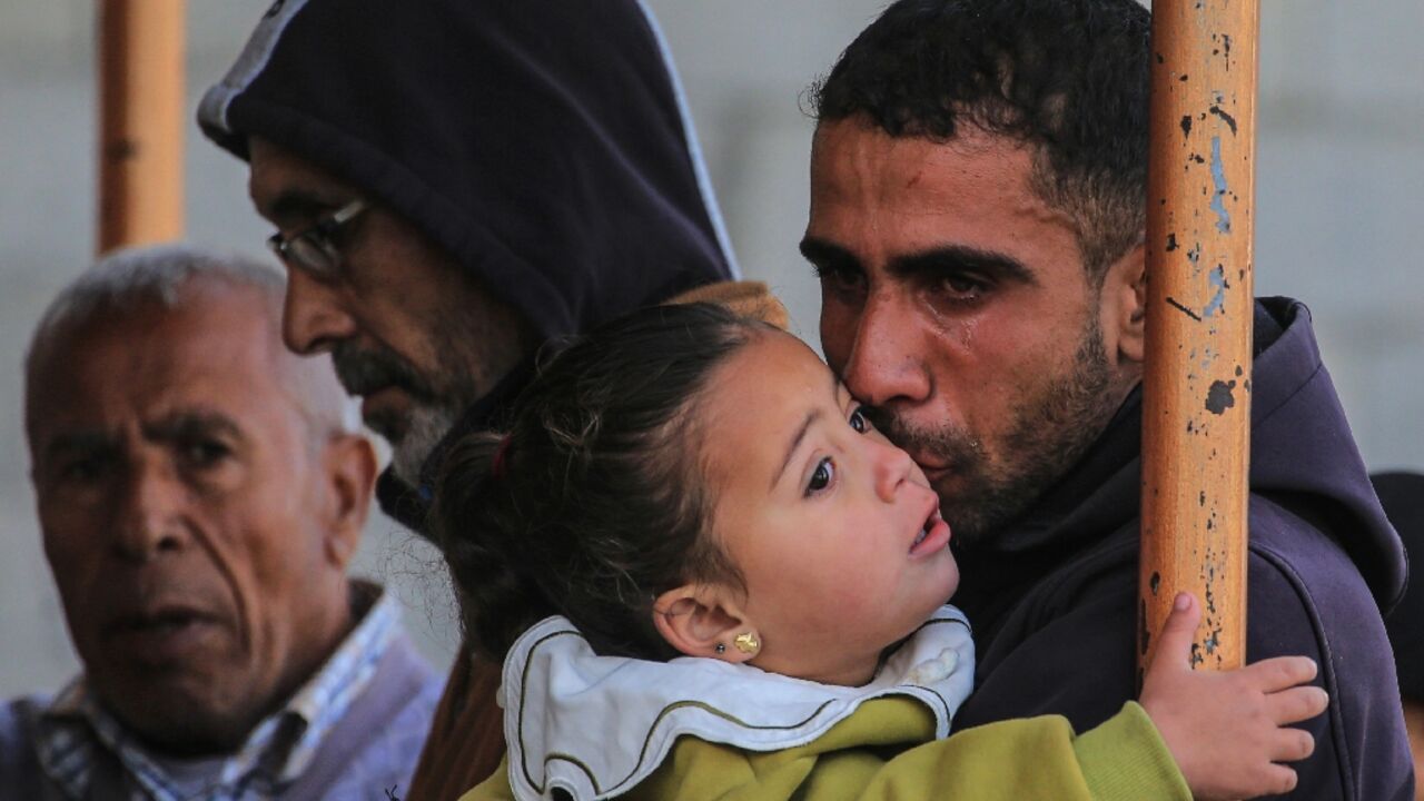 A mourner at Nasser Hospital in Khan Yunis kisses his baby daughter during the funeral of Palestinians killed in the strikes