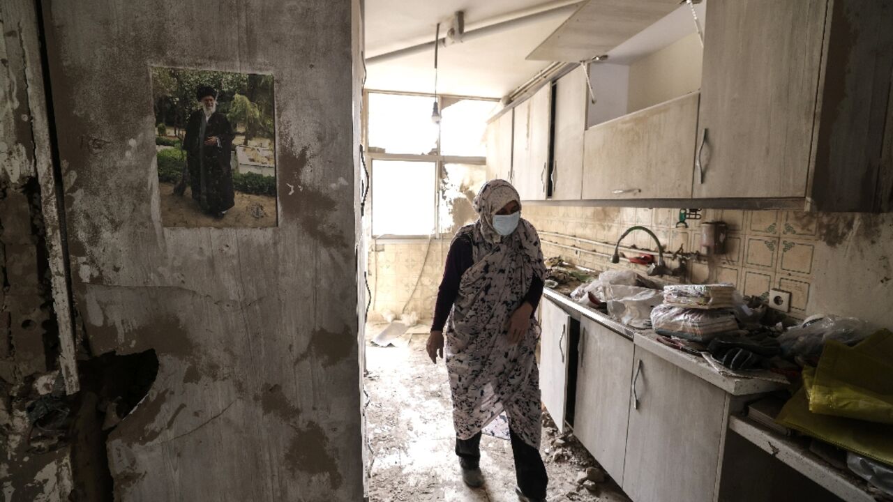 An Iranian woman walks through the destroyed kitchen in a home following a military strike in the Iranian capital Tehran on March 15, 2026