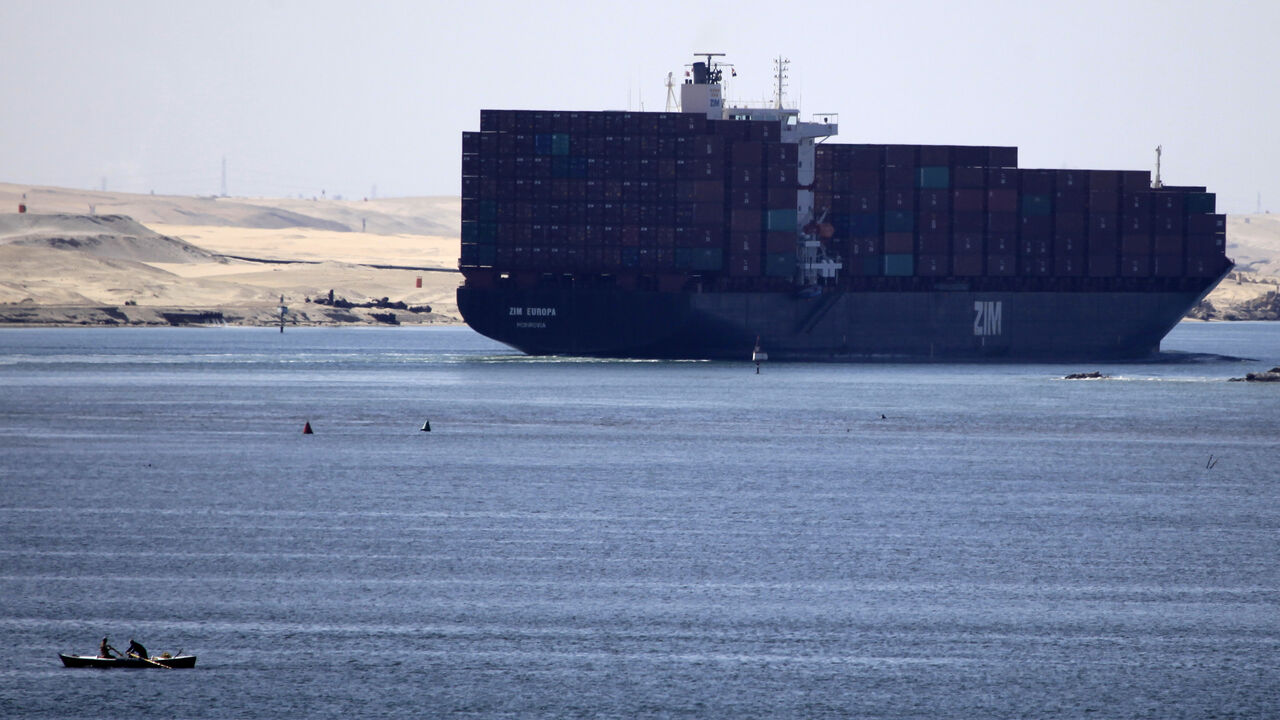 FILE PHOTO: A fisherman travels on a boat with his family in front of the Zim container ship near Ismailia port city, northeast of Cairo May 1, 2014/ File Photo