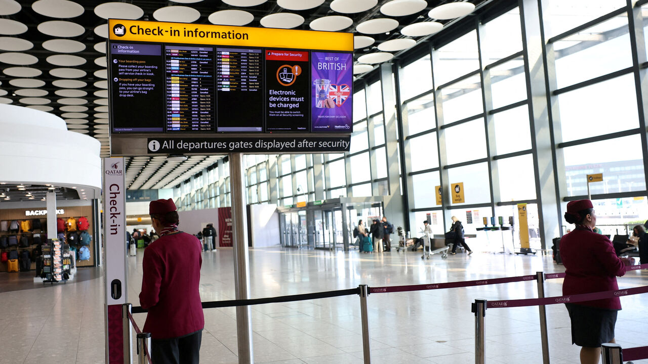 FILE PHOTO: Qatar airline staff stand by a departure board displaying cancelled flights to Middle East countries amid the U.S.-Israel conflict with Iran, at Heathrow Airport Terminal 4, in Greater London, Britain, March 2, 2026. REUTERS/Isabel Infantes/File Photo