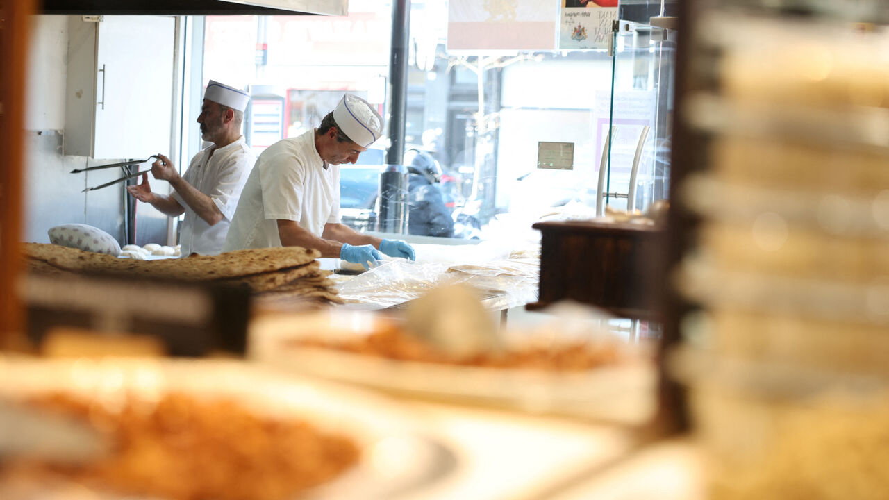 A sign in support of Reza Pahlavi, the exiled son of Iran's last shah, is displayed as men make bread at Tavazo, a Persian patisserie in Finchley, an area known for a high concentration of Persian businesses and home to a large Iranian community, in London, Britain, March 4, 2026. REUTERS/Isabel Infantes