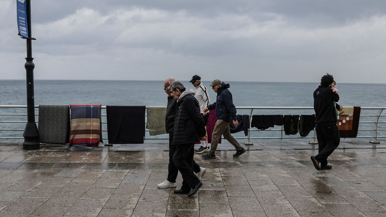 People walk past belongings left out to dry at the corniche after rainfall, following an escalation between Hezbollah and Israel, amid the U.S.-Israeli conflict with Iran, in Beirut, Lebanon, March 15, 2026. REUTERS/Khalil Ashawi