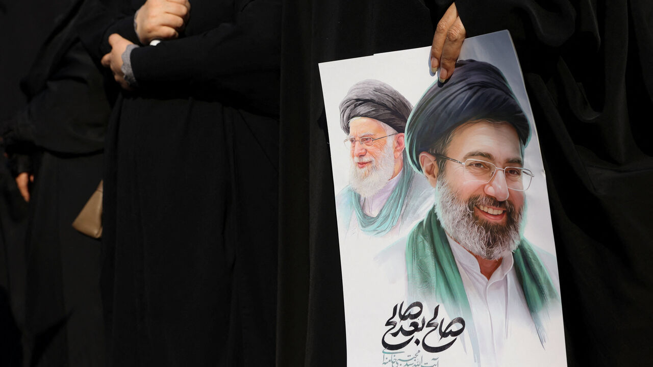 A woman holds an image of Iran's new supreme leader, Mojtaba Khamenei, alongside late Iranian Supreme Leader Ayatollah Ali Khamenei, during a funeral ceremony for the Iranian military commanders who were killed in strikes, amid the U.S.-Israeli conflict with Iran, in Tehran, Iran, March 11, 2026. Majid Asgaripour/WANA (West Asia News Agency) via REUTERS/File Photo