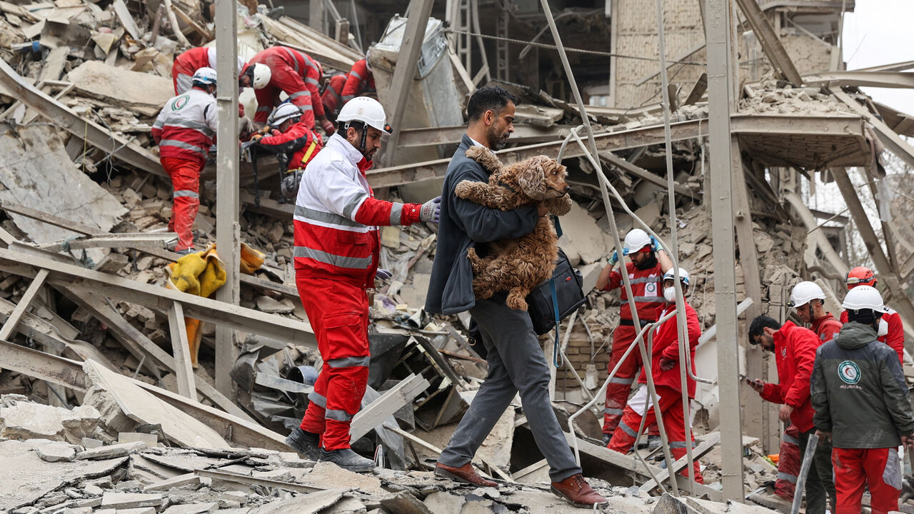 A man carries a dog as emergency personnel work at the site of a strike on a residential building, amid the U.S.-Israeli conflict with Iran, in Tehran, Iran, March 16, 2026. Majid Asgaripour/WANA (West Asia News Agency) via REUTERS