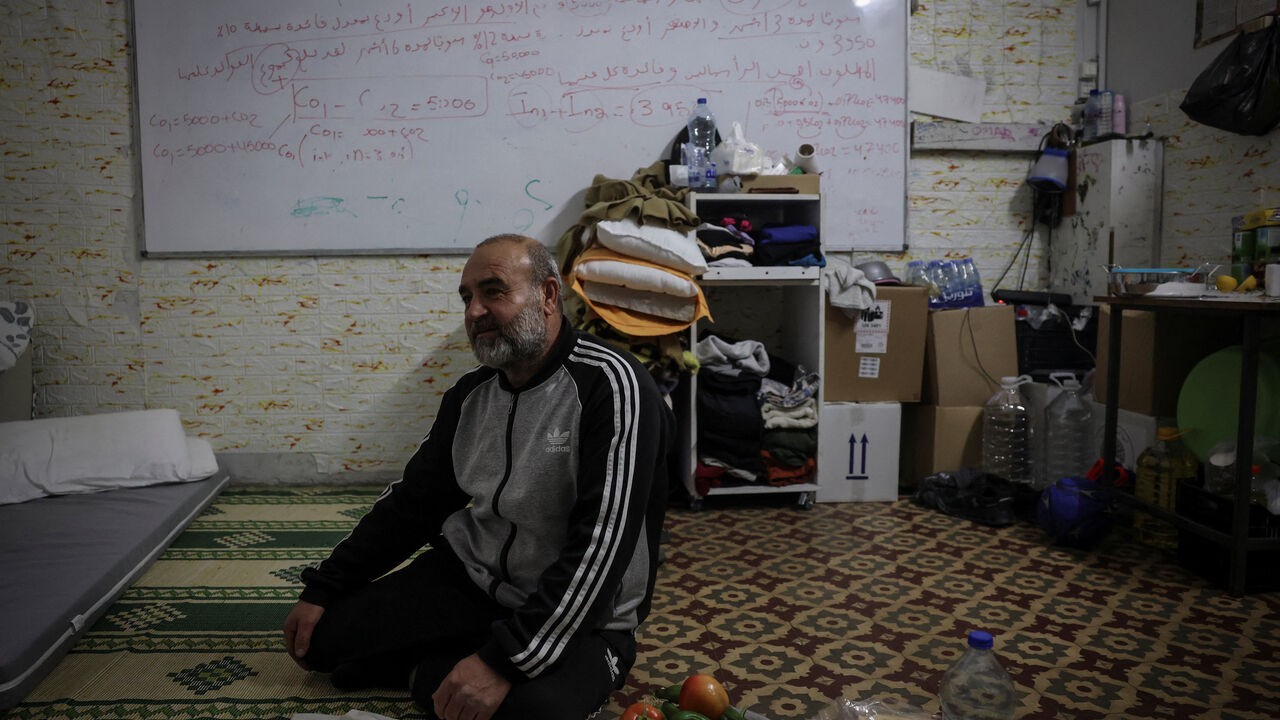 Hani Ghadban, 56, from southern Lebanon, sits on the floor as he prepares to break his fast at iftar during Ramadan, as his family takes refuge in a school that has been turned into a shelter, following an escalation between Hezbollah and Israel amid the U.S.-Israeli conflict with Iran, in Beirut, Lebanon, March 16, 2026. REUTERS/Claudia Greco