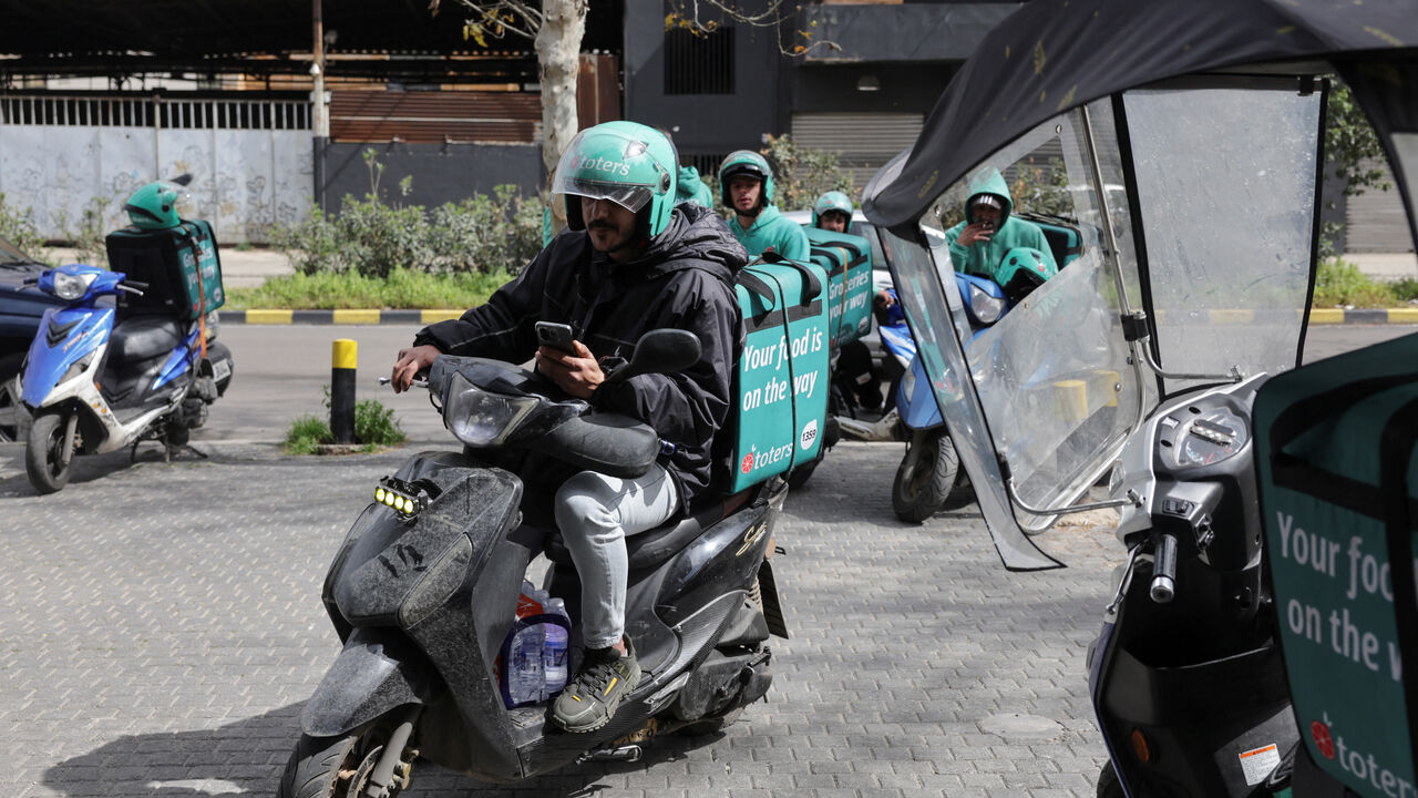 People who work as delivery drivers for the Toters delivery app sit on their scooters outside a delivery center in Beirut, Lebanon, March 18, 2026. REUTERS/Emilie Madi