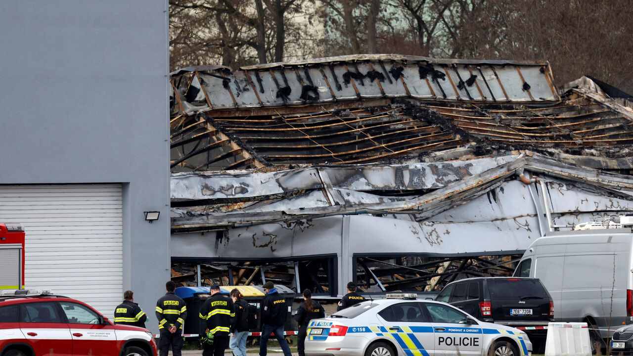 Police officers and a firefighters stand in front of a burned production hall at an industrial area in Pardubice, Czech Republic, March 20, 2026. REUTERS/David W Cerny