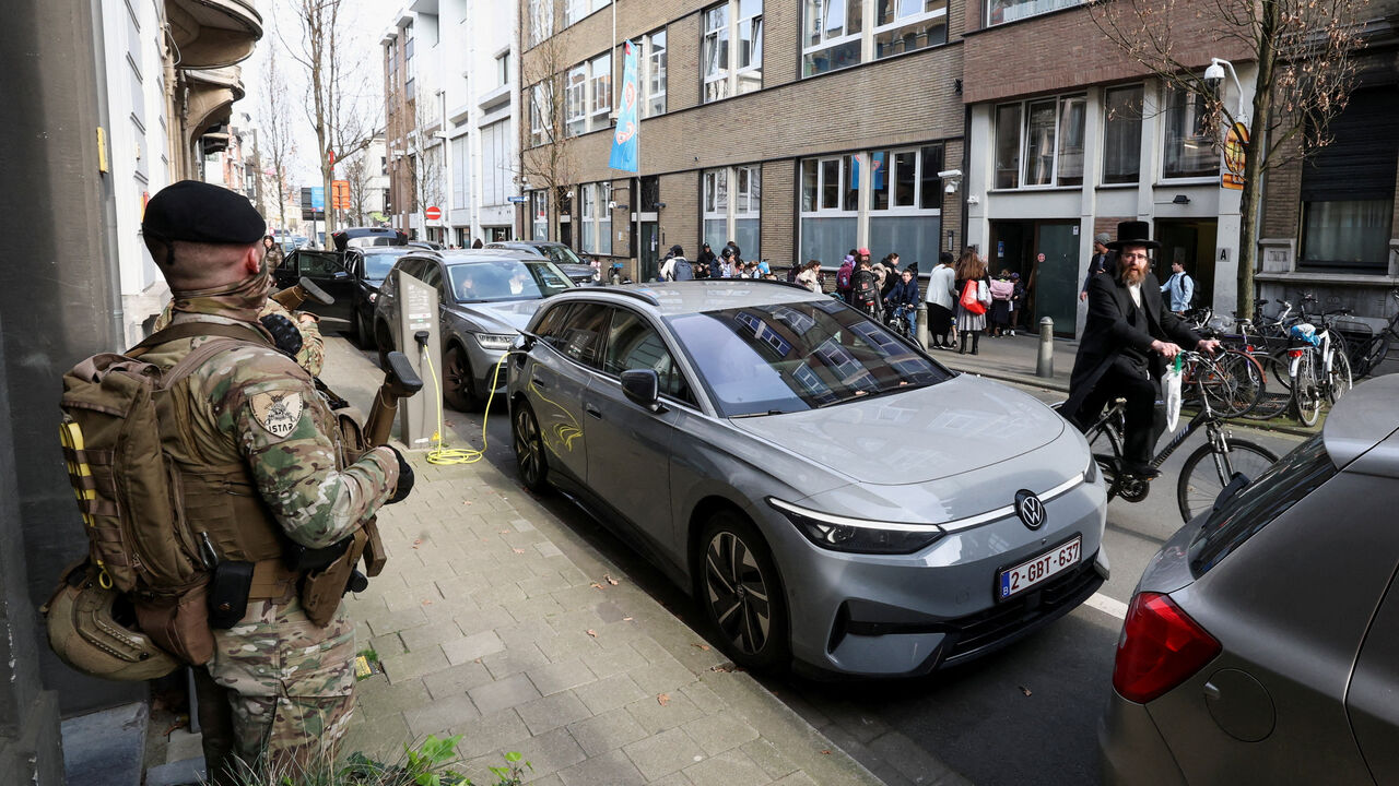 A Jewish man rides past Belgian army personnel patrolling a street as part of a deployment of soldiers outside Jewish institutions in Antwerp and Brussels following attacks at Jewish sites in Belgium and other European countries, in Antwerp, Belgium, March 23, 2026. REUTERS/Yves Herman