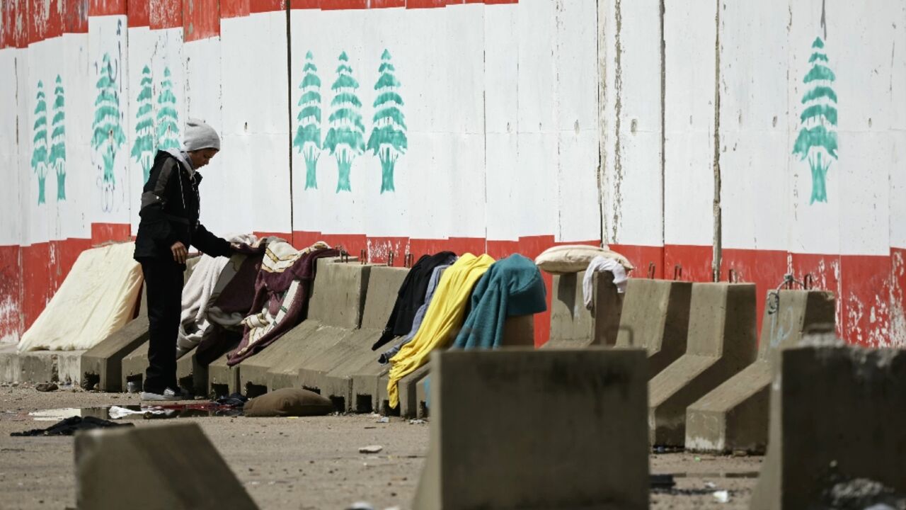 A man lays out his laundry at a parking lot in Beirut where people displaced by Israel have set up tents, on March 22