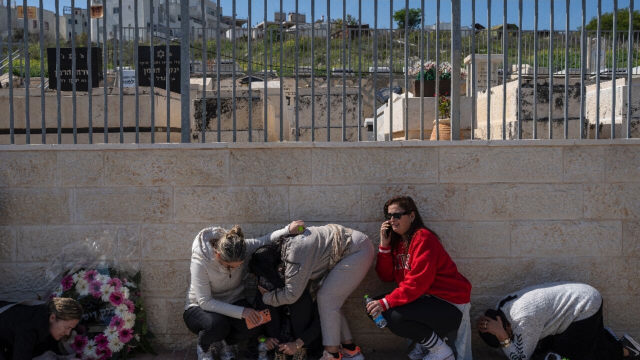 People take cover as a war siren blasts during the funeral of Sarah and Ronit Elimelech, who were killed the previous day in an Iranian missile attack, in Bet Shemesh on March 2, 2026