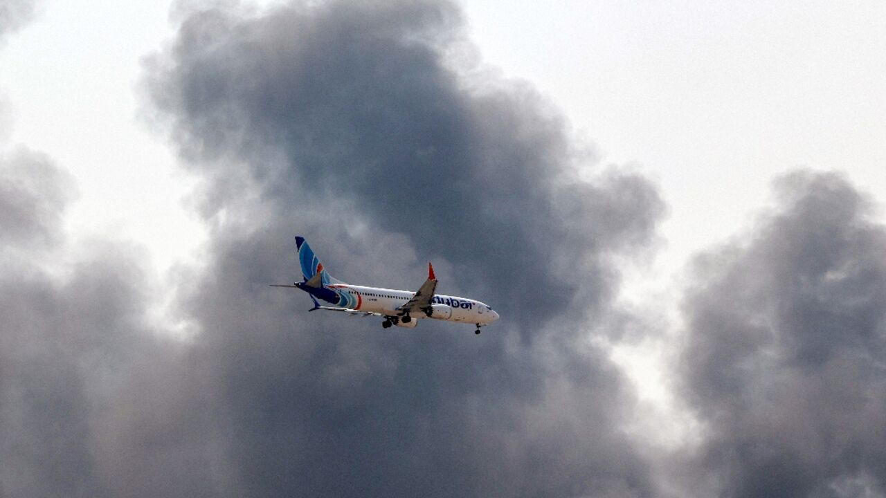 A plane comes into land as smoke rises near Dubai International Airport 
