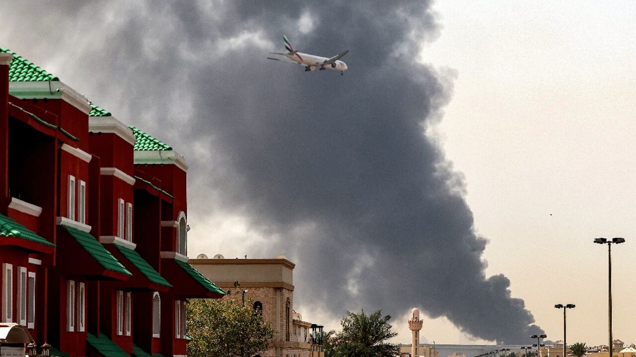 A plane comes into land as smoke rises near Dubai International Airport 