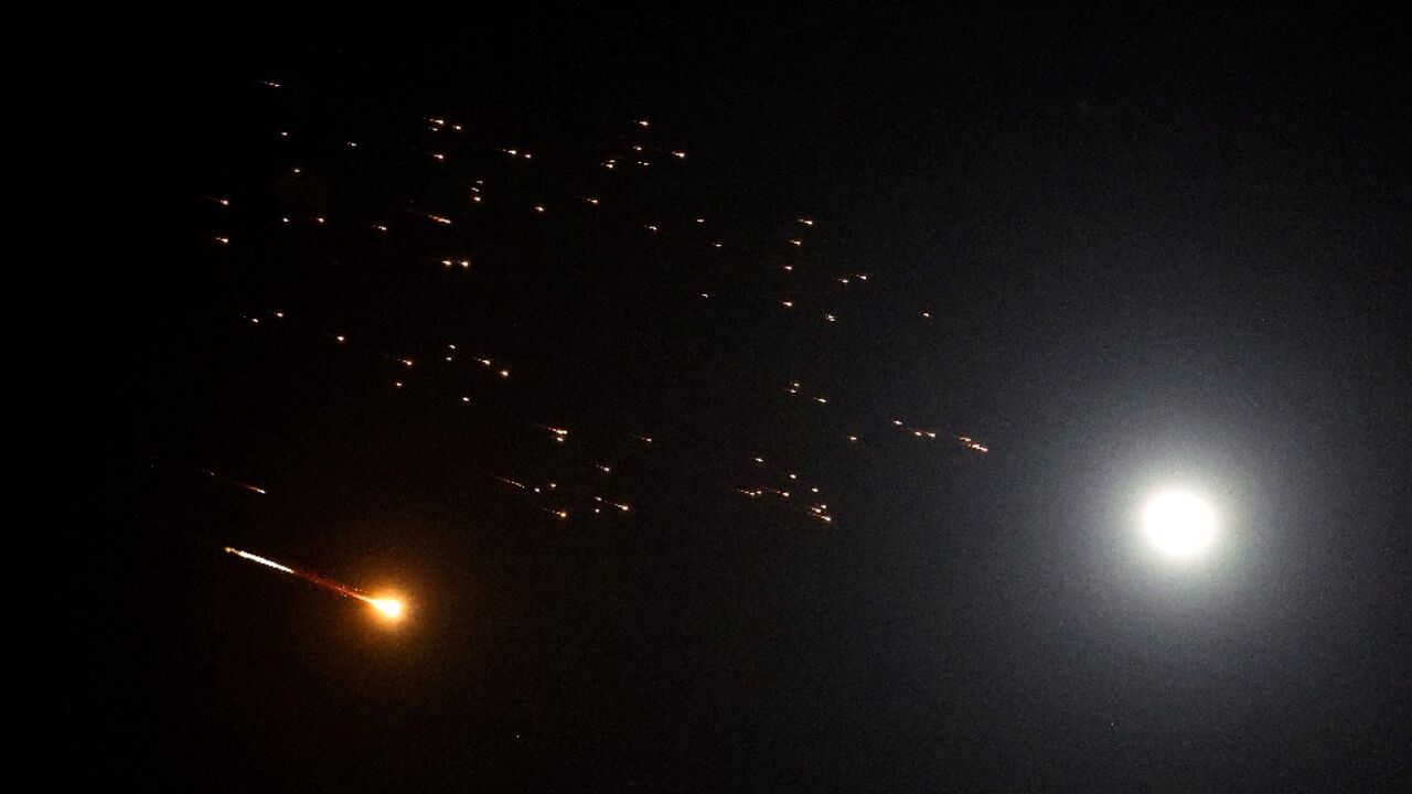 Rocket trails are seen next to the moon in the sky above Netanya