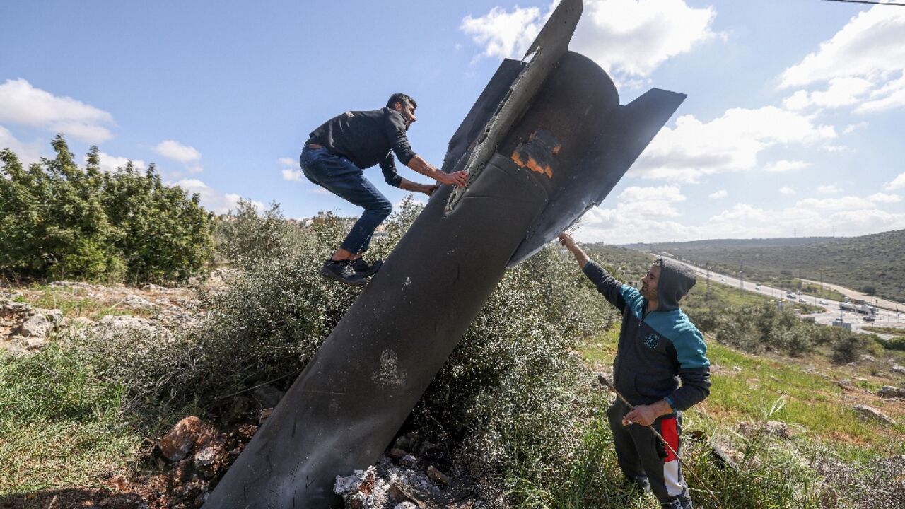 A Palestinian man climbs on the Iranian missile remnant that landed in the Israeli-occupied West Bank 