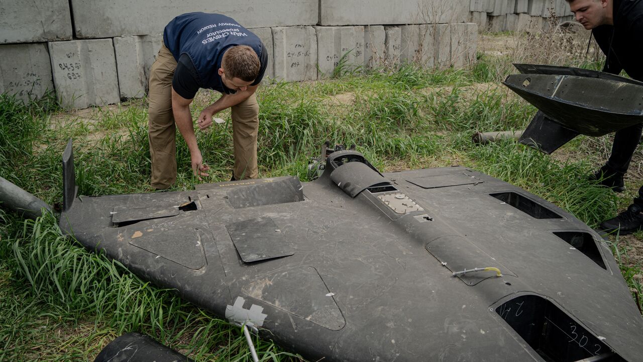 Dmytro Chubenko, spokesperson of the Kharkiv prosecutor, and his assistant look at a Russian Shahed drone shot down by Ukraine's air defense forces in a field used for the storage of Russian missiles in Kharkiv, on April 30, 2025.