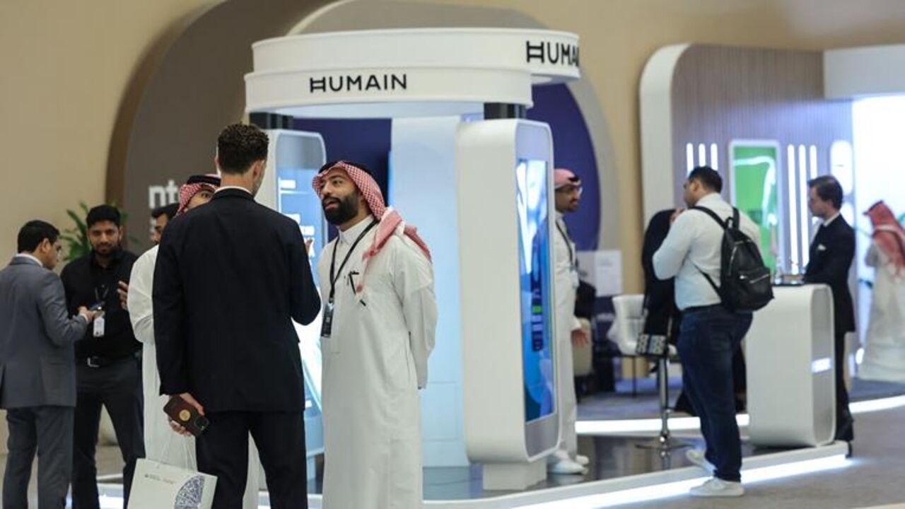 Guests stand at the booth of Saudi artificial intelligence company Humain during the Future Investment Initiative (FII) conference in Riyadh on October 29, 2025. Saudi Arabia kicked off a major investment conference featuring heads of state and the global business elite on October 28 as it seeks support for its sprawling "gigaprojects" and sky-high AI ambitions. (Photo by Fayez Nureldine / AFP) (Photo by FAYEZ NURELDINE/AFP via Getty Images)
