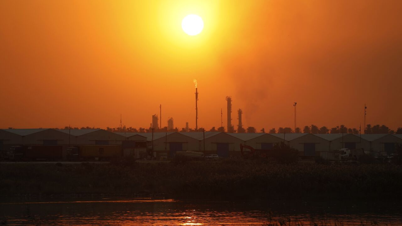 The sun sets behind burning gas flares at the Dora Oil Refinery Complex in Baghdad on Nov. 24, 2025. 