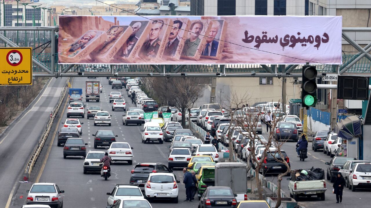 Traffic rolls along a main throughfare under a banner with images of past and present leaders that reads in Farsi, "Domino fall", as daily life returns to the streets following nationwide protests, in the Iranian capital Tehran on January 19, 2026. Demonstrations sparked in late December by anger over economic hardship exploded into protests widely seen as the biggest challenge to the Iranian leadership in years. Limited internet access briefly returned in Iran before dropping again, a monitor said January 
