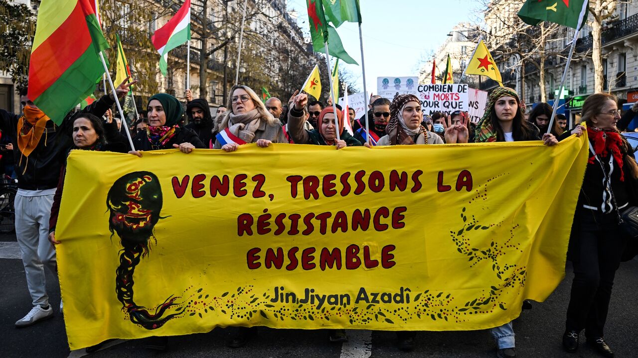 Protesters hold a banner reading "Come and weave resistance together" and "Women, life, freedom." 
