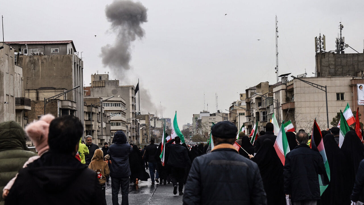 Black smoke rises following an airstrike, as Iranians take part in the Al-Quds (Jerusalem) Day rally, a commemoration in support of the Palestinian people on the last Friday of the Islamic holy month of Ramadan, in Tehran on March 13, 2026. 