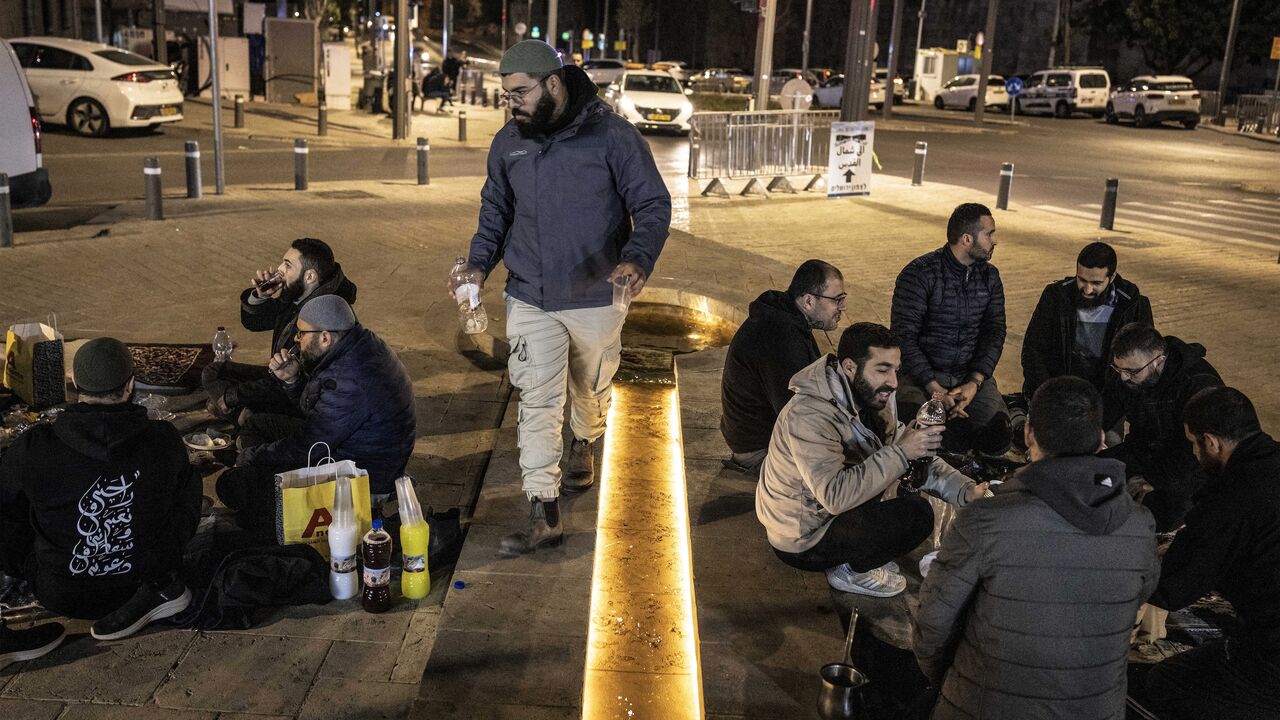 Muslim worshippers break their fast outside the old city walls of Jerusalem on March 17, 2026, as the Al-Aqsa Mosque compound remains closed. 
