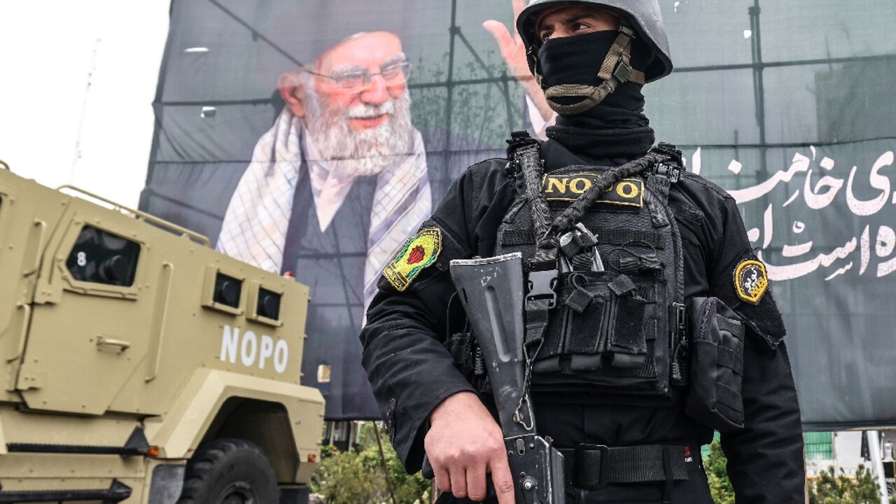 A member of the Iranian security forces stands guard next to a banner honouring Iran's slain supreme leader Ayatollah Ali Khamenei in Tehran 