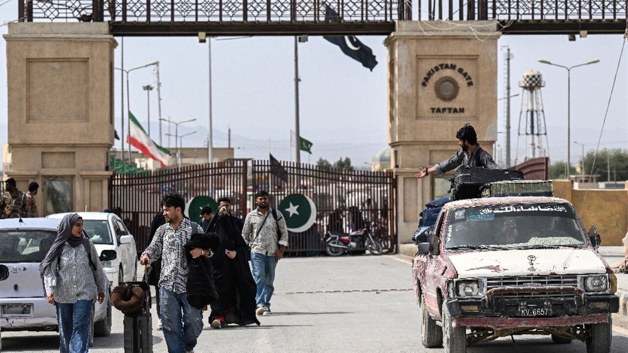 Pakistani nationals walk across the Taftan border after returning from Iran