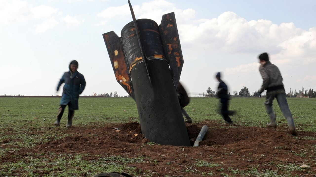 Children play around an unexploded missile that landed in an open field on the outskirts of Qamishli, eastern Syria