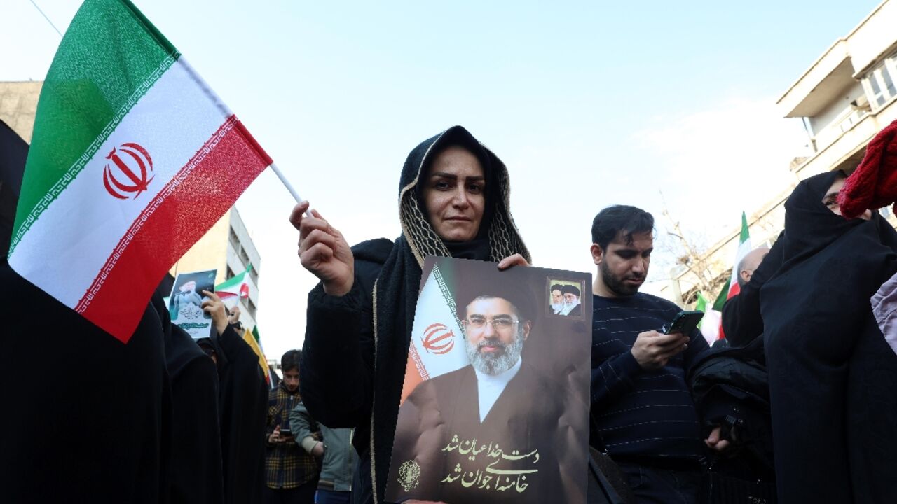 A demonstrator holds a picture of Iran's new supreme leader Ayatollah Mojtaba Khamenei as people gather for a rally to support him in Tehran