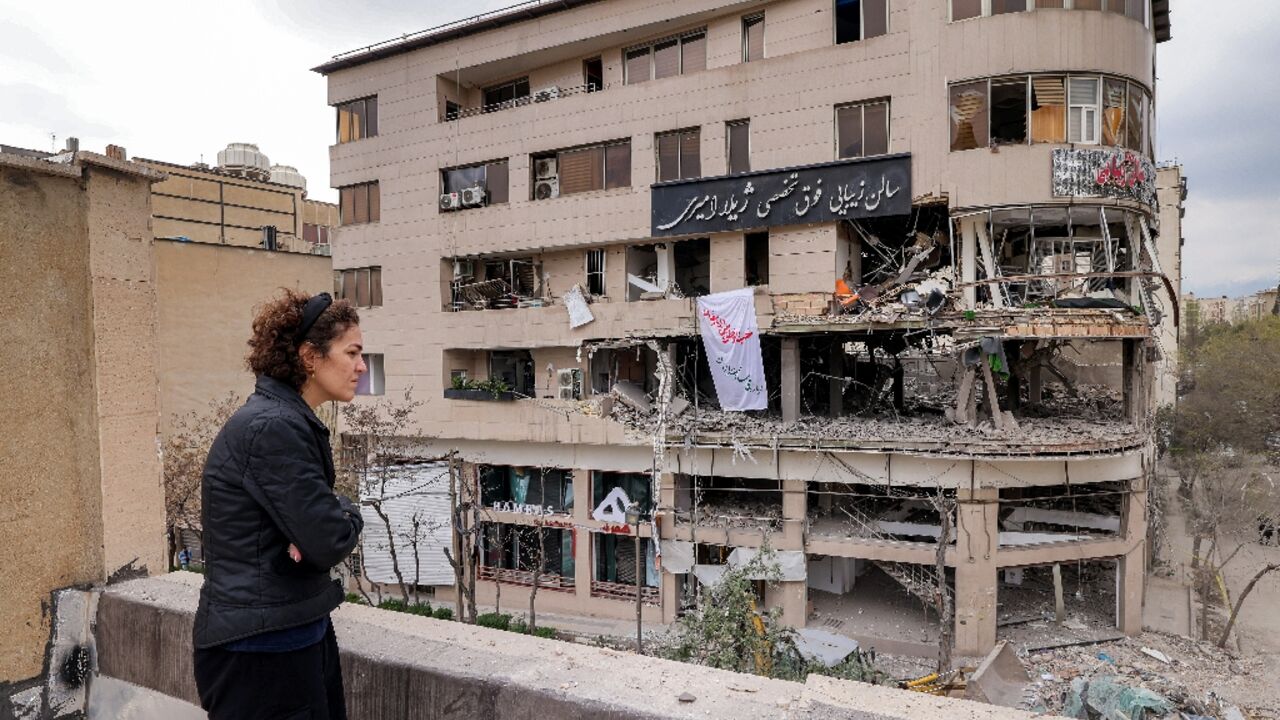 A woman surveys damage to a Tehran building that housed the offices of Qatari news network Al Araby TV following a missile strike