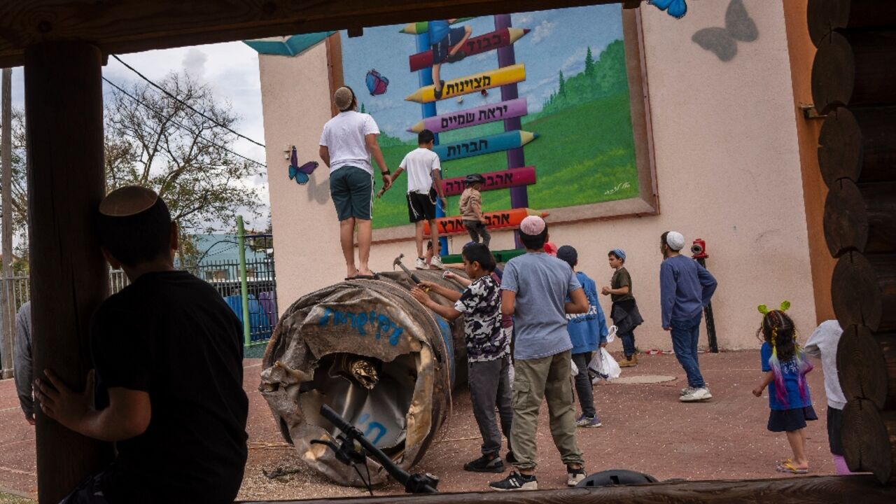 Children play with the remnant of an Iranian missile that fell in a school courtyard in the illegal Israeli settlement of Peduel, in the occupied West Bank