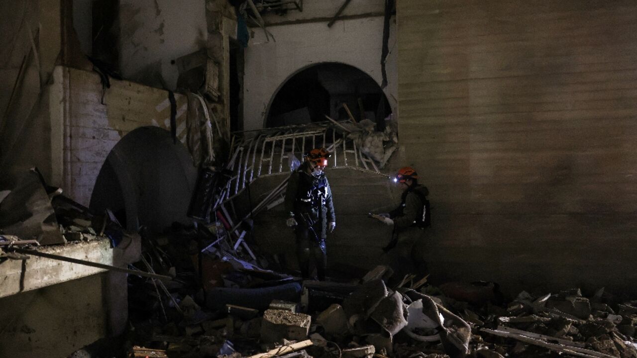 First responders inspect the site of an Iranian missile strike in Arad early on March 22, 2026