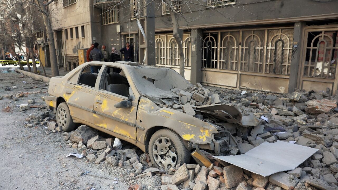 Residents stand amid the debris of a building following air strikes in central Tehran