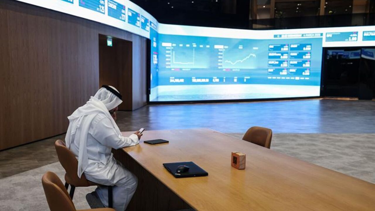 A man sits by a screen displaying stock indices at the Dubai Financial Market (DFM) stock exchange in Dubai on Mar. 4, 2026. — Fadel SENNA / AFP via Getty Images